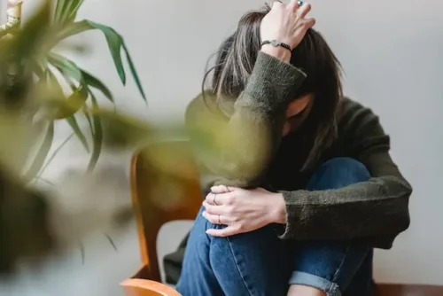 a woman sitting on a chair while feeling stressed