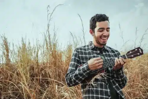 Man playing the ukulele in a field