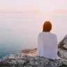 woman sitting on a cliff near the sea