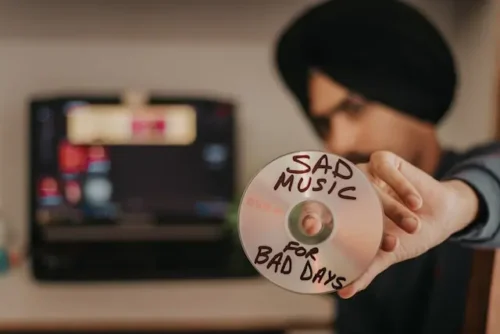 Person holding a CD with sad songs on it