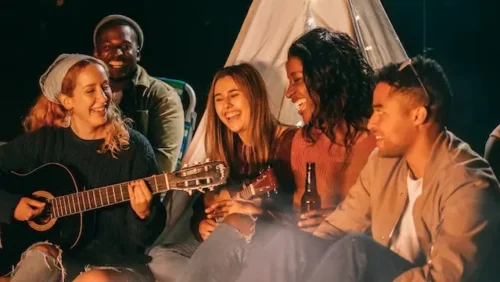 Group of people sitting next to a campfire and singing to symbolize the power of music in promoting mental health