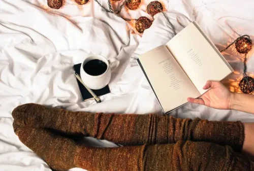 a girl with socks in bed holding a book