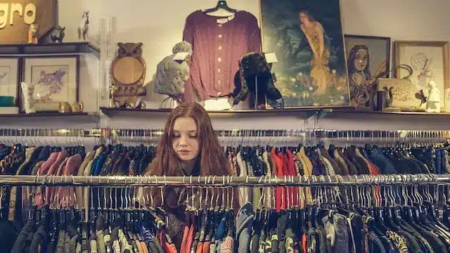 A person looking through clothes in a thrift store as one of the ethical and spiritual dimensions of mindful shopping