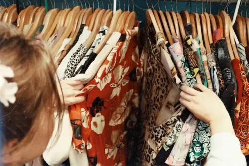 Person looking through clothes on a rack in a thrift store