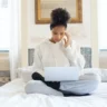 Woman sitting on a bed and researching how to stay motivated when working on long-term goals