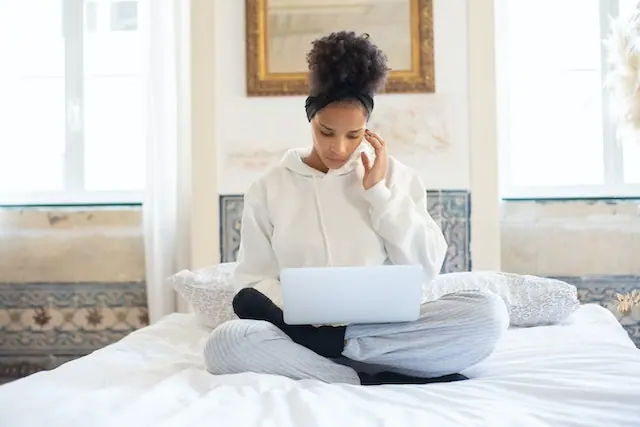 Woman sitting on a bed and researching how to stay motivated when working on long-term goals