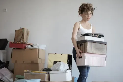 Woman holding boxes next to a pile of clutter