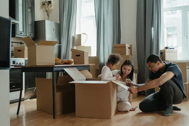 Parents and their child labeling moving boxes