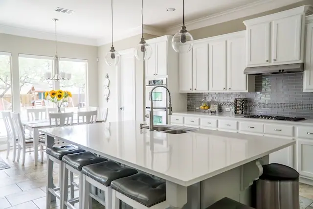 A big kitchen with a white table, countertops and shelves.