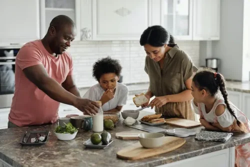 Parents and their two children making breakfast in the kitchen.