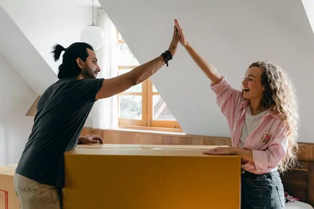 Happy couple high-fiving each other over a moving box after creating a moving budget