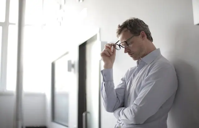 A stressed man holding his glasses