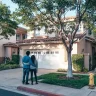 Couple standing in front of their new home, reflecting on maintaining a minimalist lifestyle post-move with intention and simplicity.