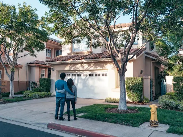 Couple standing in front of their new home, reflecting on maintaining a minimalist lifestyle post-move with intention and simplicity.