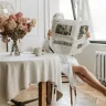 A person in a robe reads the newspaper by a bright window, enjoying a morning routine that grounds you in a new home.