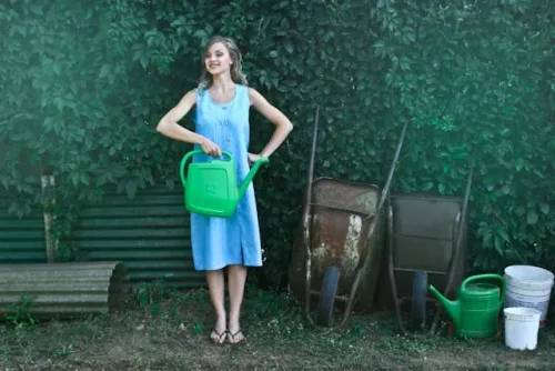A person holding a green watering can Seasonal