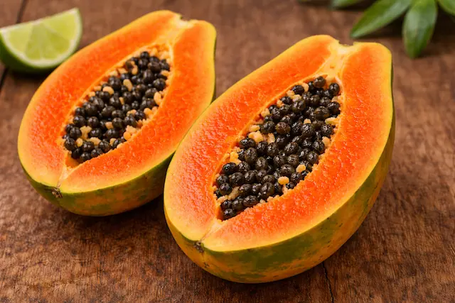 Ripe papaya cut in half showing bright orange flesh and black seeds illustrating what does papaya taste like and the fruit's soft juicy texture
